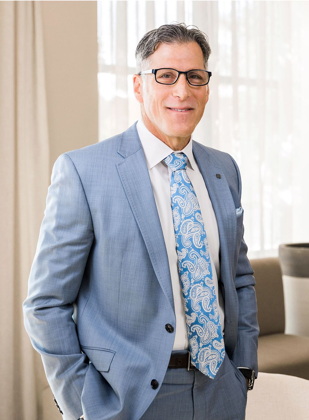 Smiling man in suit with paisley tie.