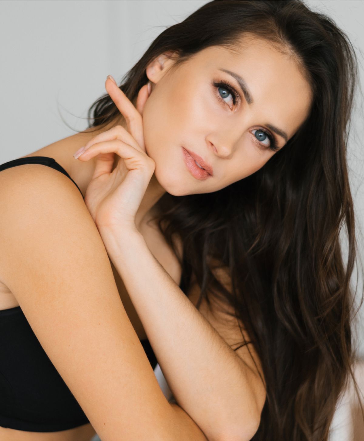 Woman with long hair posing thoughtfully indoors.