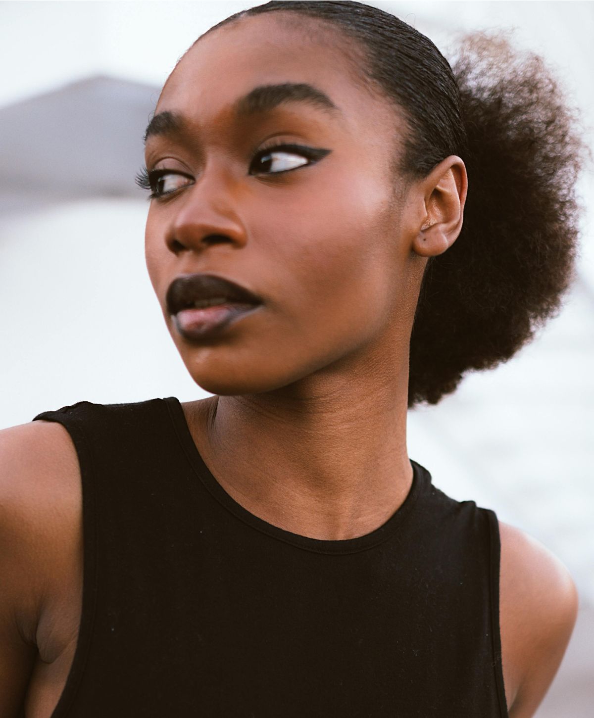 Woman with bold makeup and textured hairstyle.