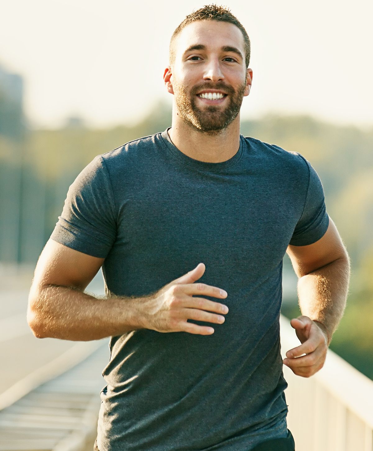Smiling man jogging outdoors in athletic attire.