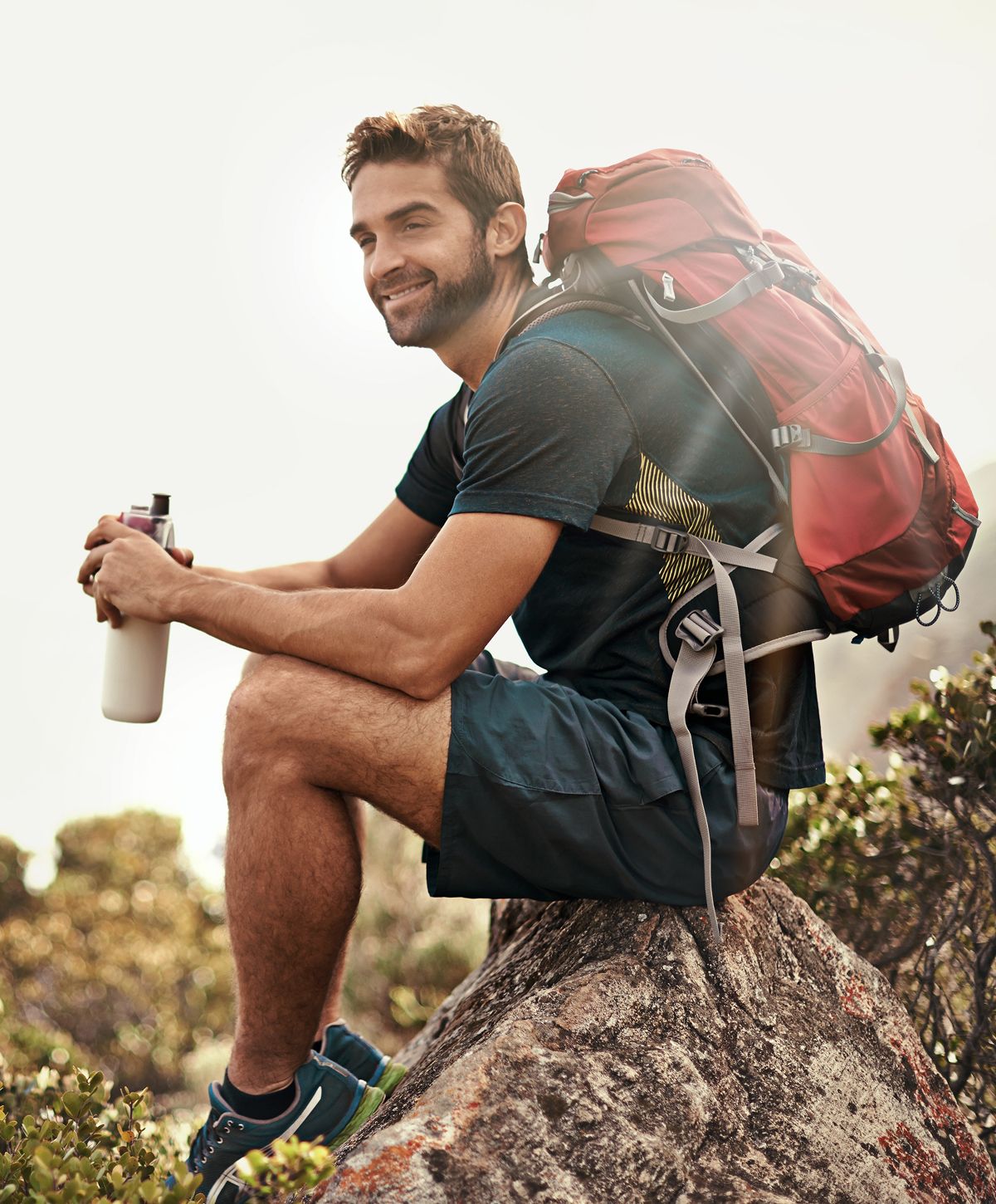 Smiling hiker resting on a rock outdoors.