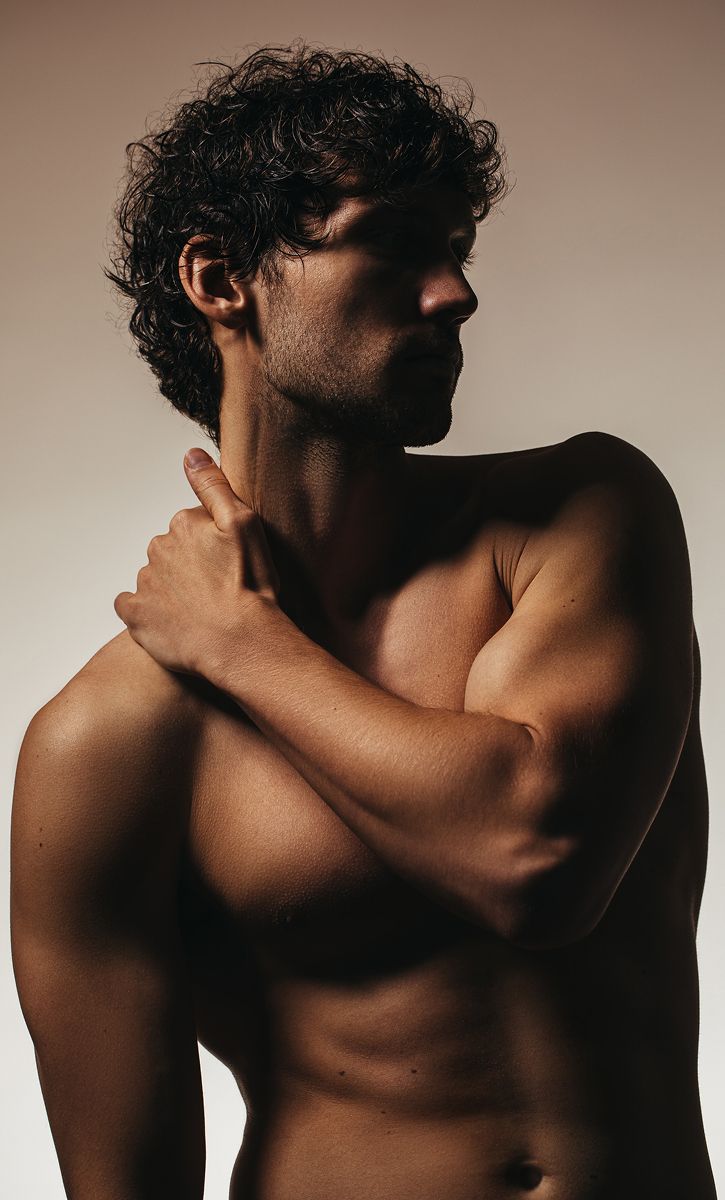 Side profile of a shirtless man posed elegantly.