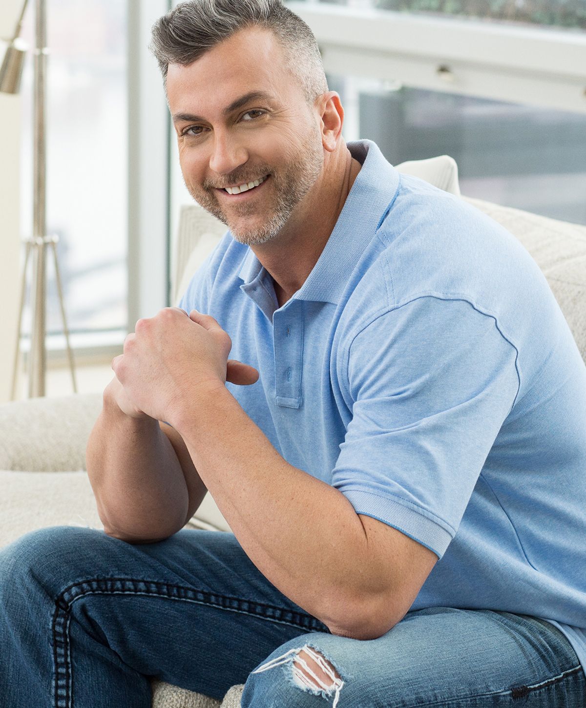 Smiling man sitting on a couch indoors.