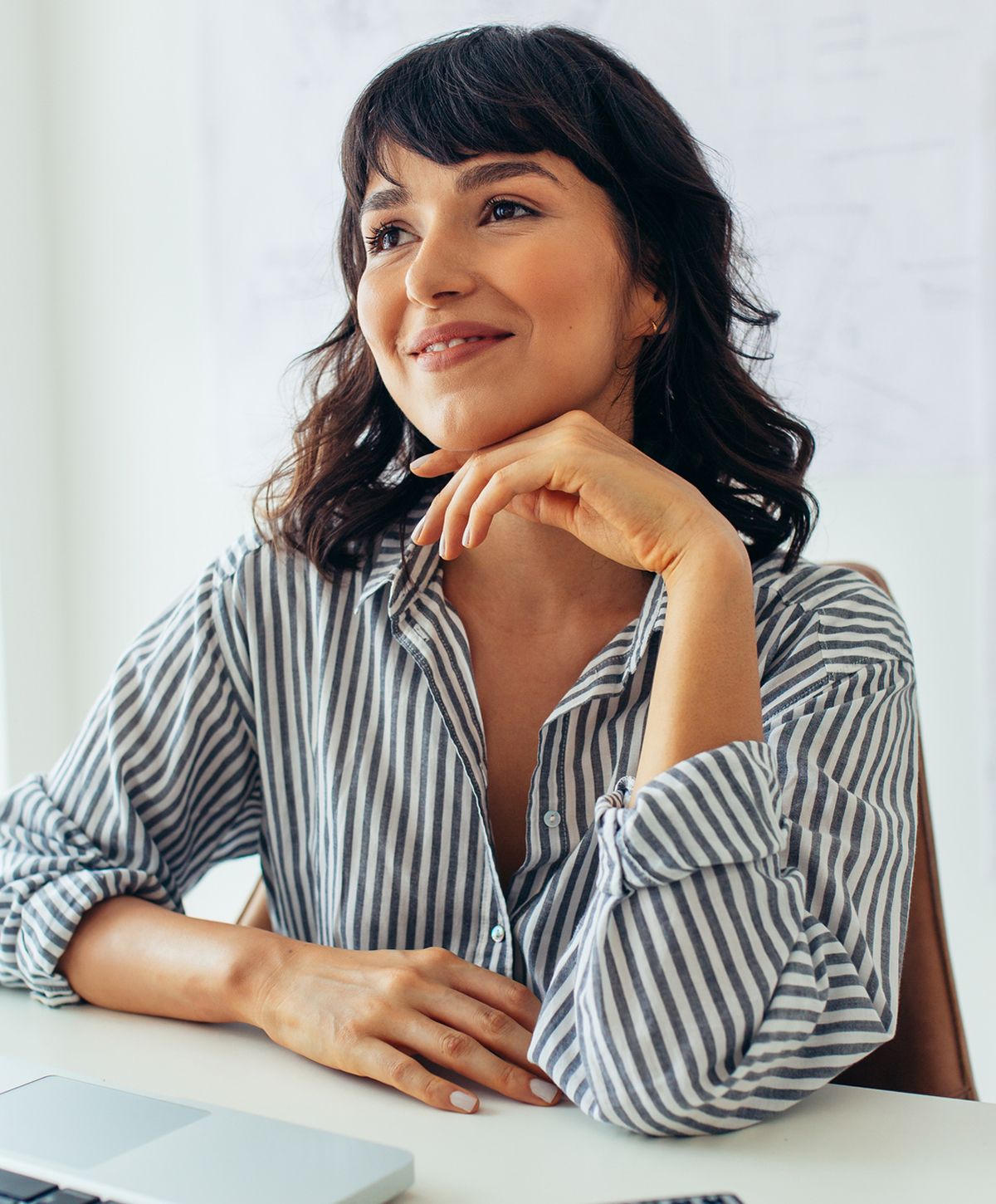 Thoughtful woman in striped shirt at desk