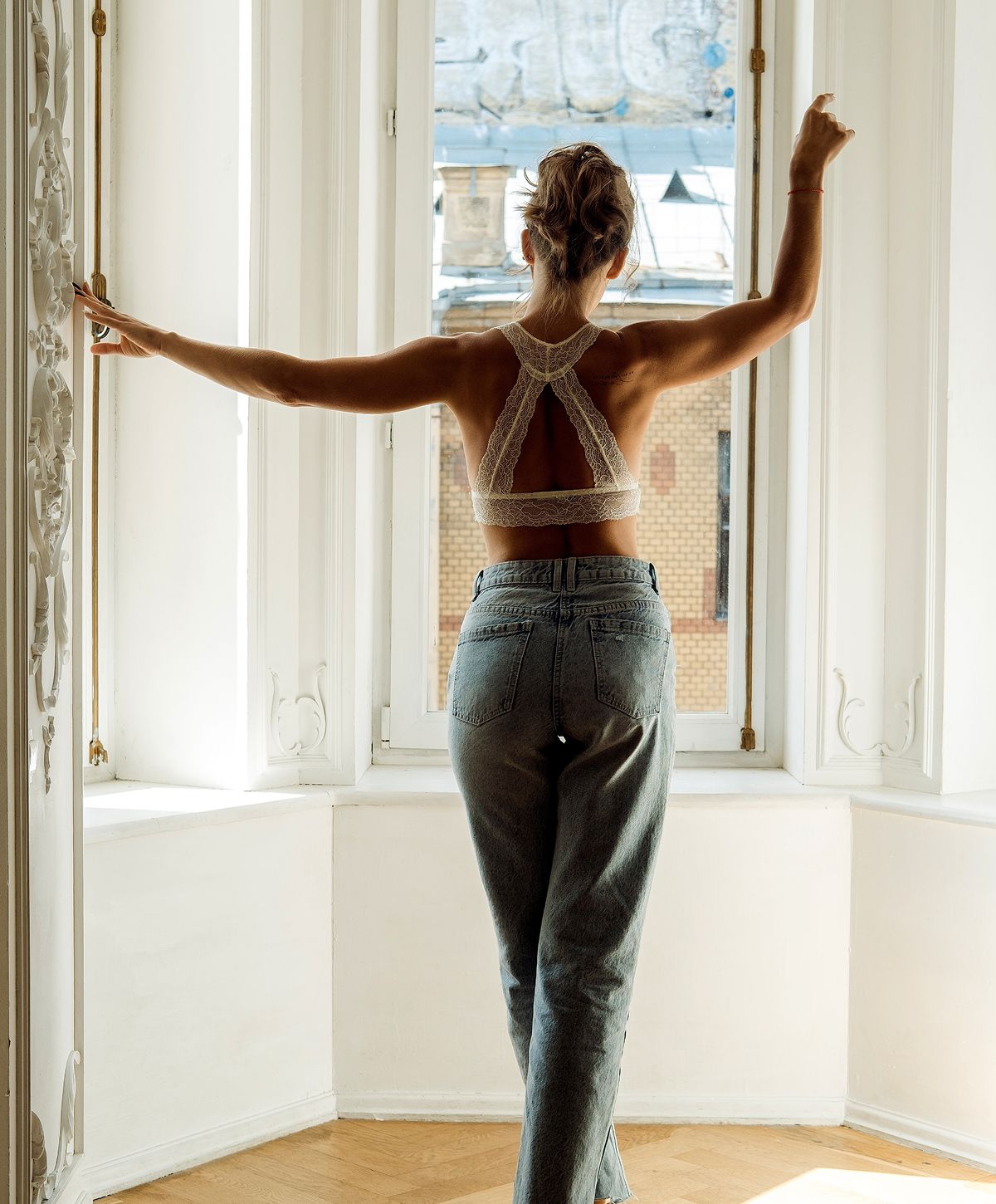 Woman in stylish lingerie poses near a wall.