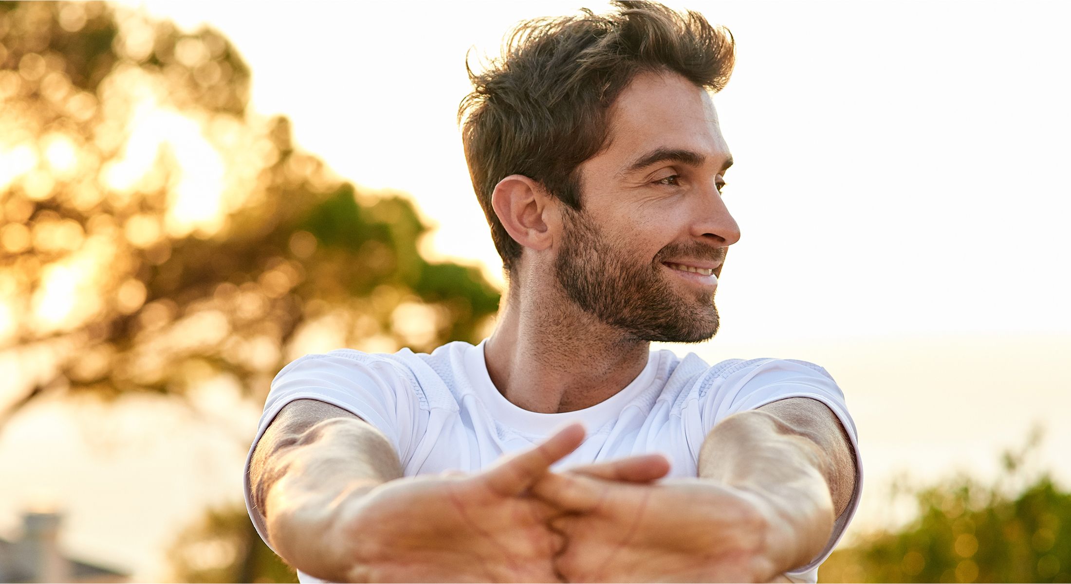 Man stretching outdoors with a sunset background.