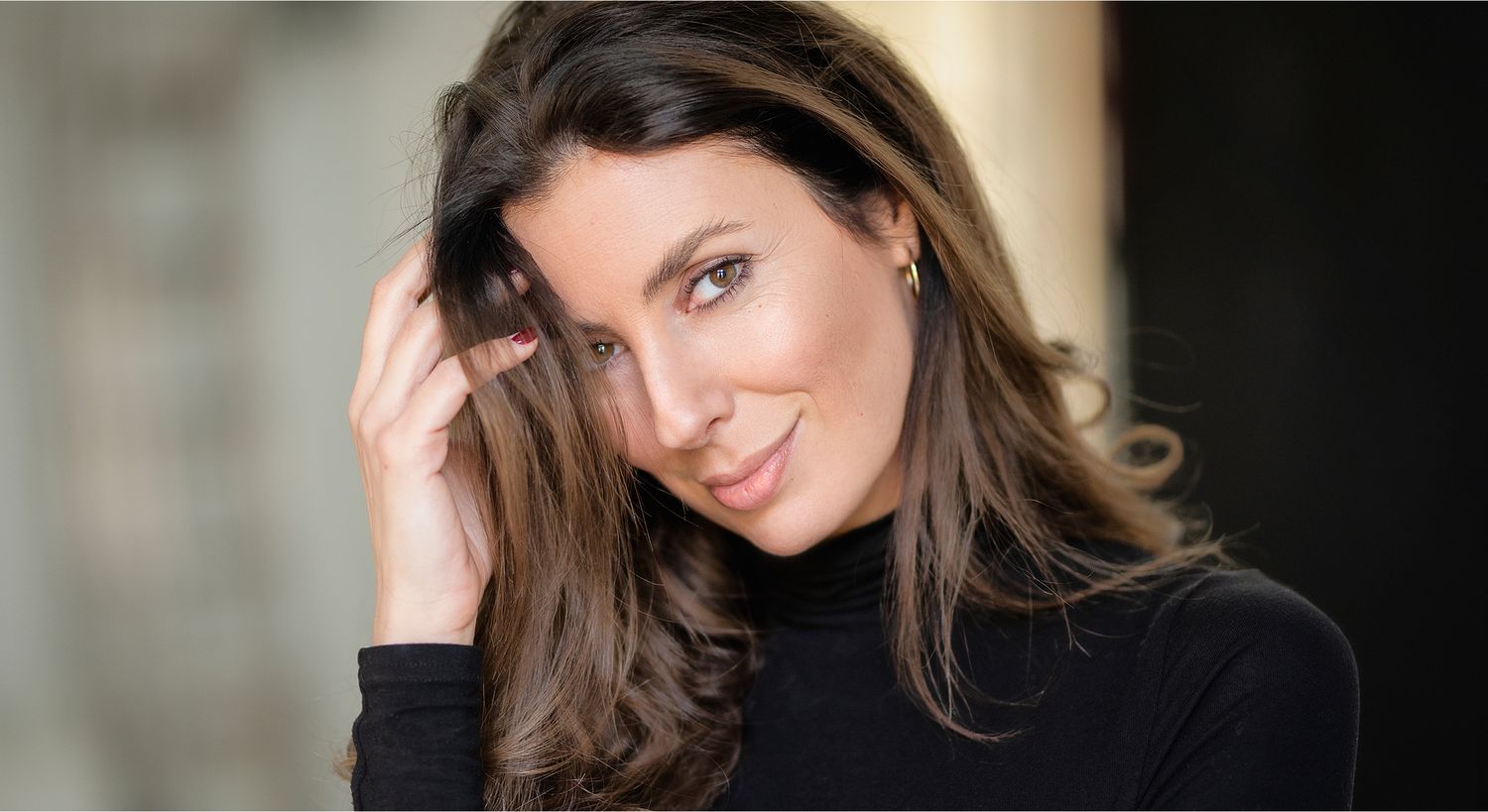 Woman in black top smiling and posing.