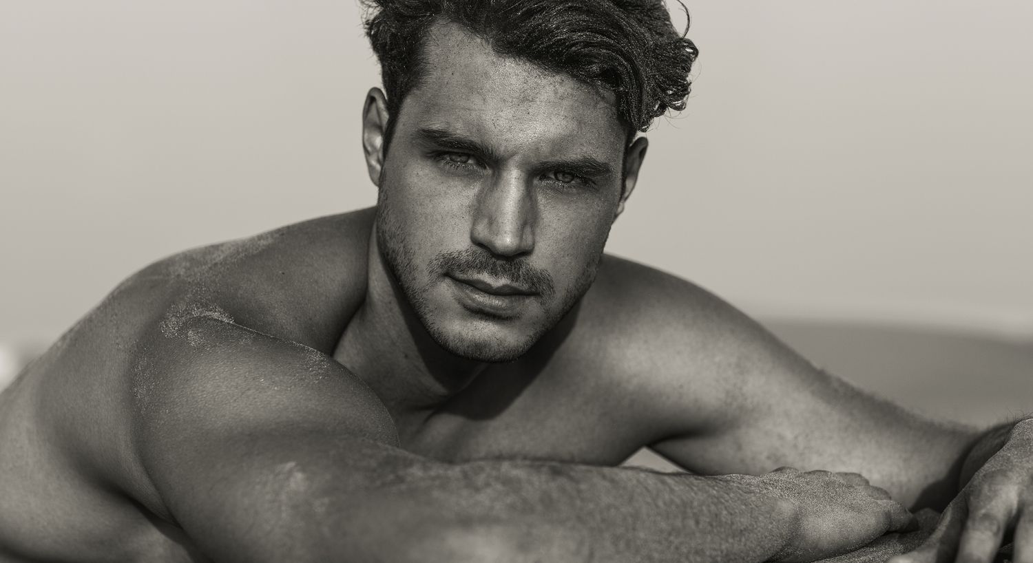 Man posing on a beach in black and white.