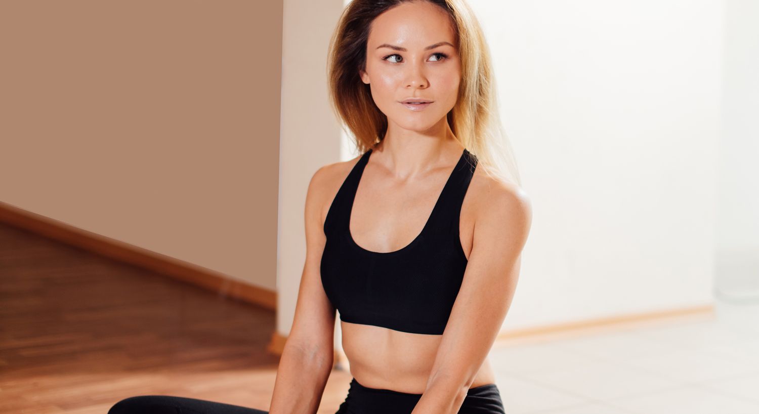 Woman in fitness attire sitting indoors.